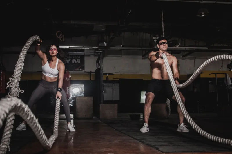 Athletes training with battle ropes in a dark gym